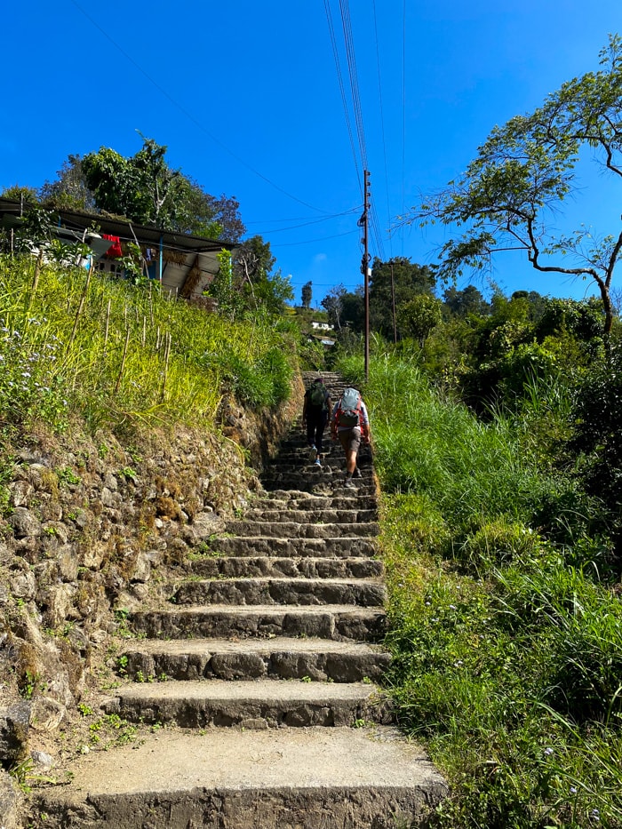 Two hikers climb a steep set of stairs through a village